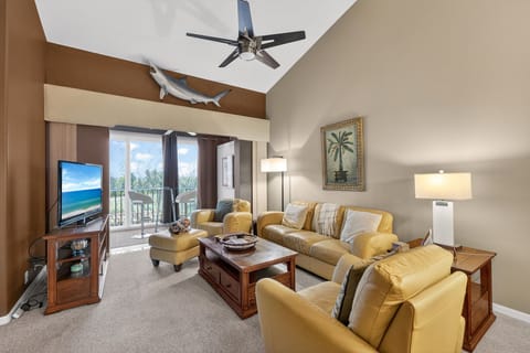 Spacious living room with vaulted ceilings, plush leather seating, and screened lanai overlooking golf course views.