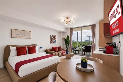 Experience modern luxury at The Standard Residences in Midtown Miami. This sunlit studio features a plush bed, sleek kitchen, cozy seating, and a private balcony with stunning city views. Perfect for your vibrant South Florida getaway.