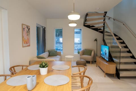 Stylish living area with dining table for 6, sofa, arm chair and smart-tv.