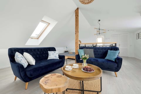 Bright and spacious living room with comfortable blue sofas, a coffee table, and plenty of natural light.
