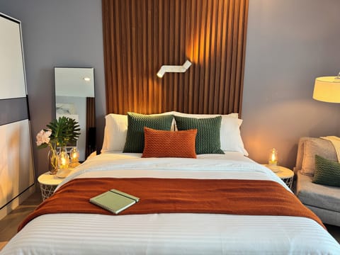 Modern cozy bedroom with wood slat headboard, candles, and plush bedding