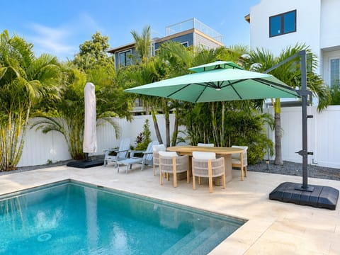 Private tropical pool patio with shaded outdoor dining and lush landscaping