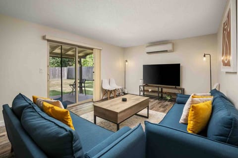 Inviting living room with comfortable seating, a large smart TV, mini-split A/C, and sliding glass doors leading to the covered patio and backyard.
