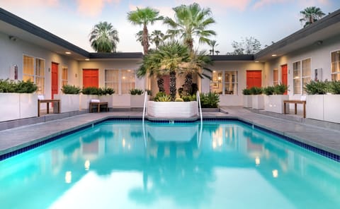 Palm-lined courtyard pool with lounge seating and a relaxed boutique-style setting.