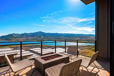Panoramic mountain and lake views from the private balcony, complete with an open fire feature and cozy seating.