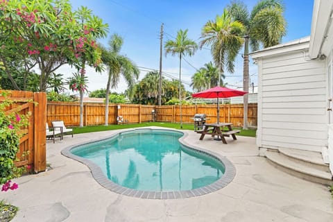 Dive into relaxation with your own sparkling, curved swimming pool surrounded by a fully fenced yard, lush tropical palm trees, and vibrant flowering greenery.