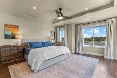 Relax in this serene bedroom featuring crisp linens, vintage-inspired décor, and natural light that streams through expansive windows overlooking peaceful treetops and open skies.
