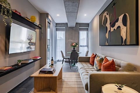 Relax in the living area, complete with a comfortable seating, a wall-mounted TV, and stylish contemporary artwork.