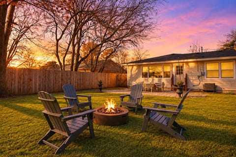 Cozy fenced backyard with fire pit, patio dining, and sunset views