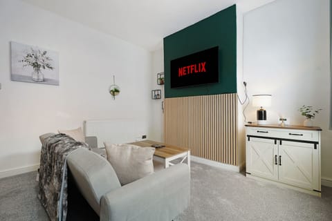 Bright and inviting living room with a comfortable sofa bed, coffee table, wall-mounted TV, free Wi-Fi, and practical storage. Unwind after a busy day or enjoy a relaxing evening with the provided cards and dominoes for a little indoor entertainment.