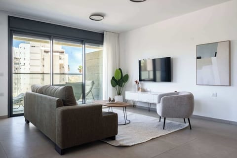 Contemporary living room with dark-framed windows, gray upholstered sofa, and minimalist white wall décor.