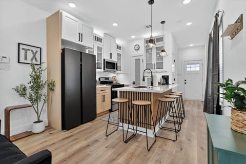 Modern chef’s kitchen with island seating, coffee bar & black appliances