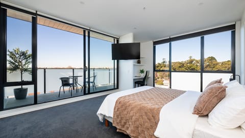 Light-filled main bedroom with expansive windows and balcony views