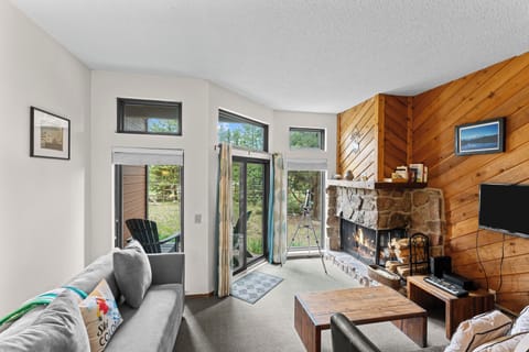 Gather around the stone fireplace in this bright living space, where large windows and patio access invite mountain views right into your retreat.