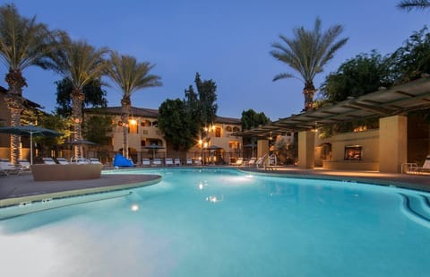 Relax by the shimmering pool, surrounded by swaying palms and soft evening lights.