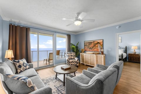Settle into your coastal retreat where soft sofas meet sweeping ocean views through your private balcony doors, inviting endless sunlit afternoons and tranquil seaside relaxation.