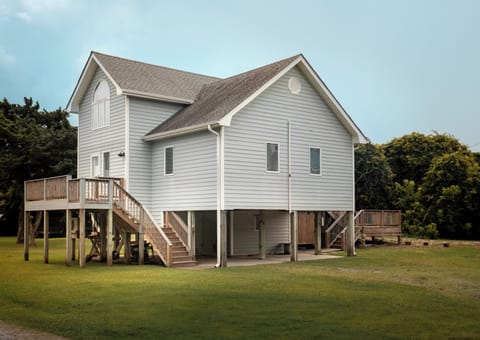 Elevated coastal retreat surrounded by lush greenery and open skies, offering a peaceful setting for your getaway with convenient stair access and plenty of outdoor space.