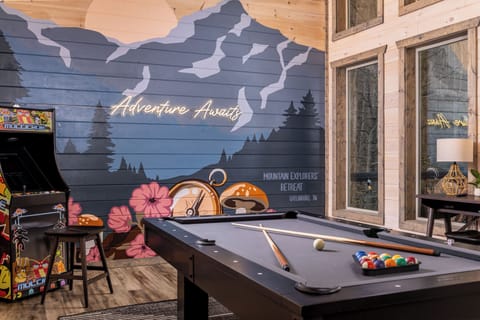 Rustic game room with pool table, arcade, and bold mountain mural