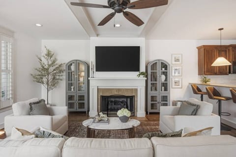 Beautifully designed living room with a fireplace, ceiling fan and plenty of comfy seating. Smart TV, wood floors, and easy flow into the kitchen.