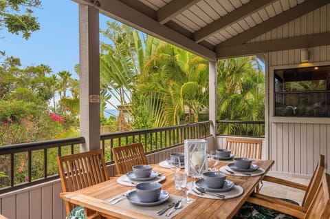 Unit 1: Enjoy outdoor dining on a private lanai surrounded by lush tropical greenery, complete with a wooden table set for a relaxing meal.