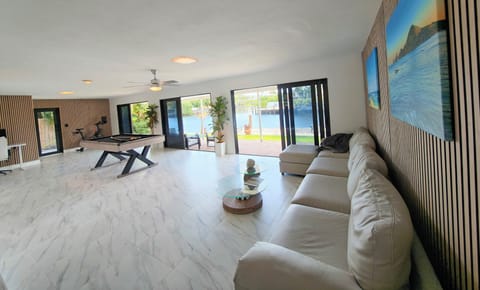 Entertaining area with TV, pool table, couch and access to the backyard and deck