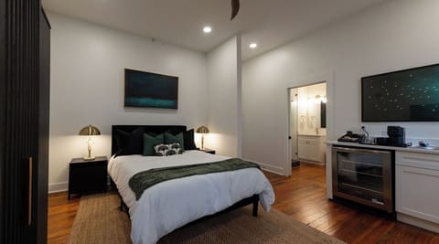 Stylish king bedroom with en-suite bath, mini fridge, and hardwood floors