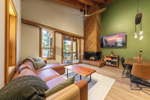 Cozy vaulted living room with fireplace, deck access, and stylish wood accents