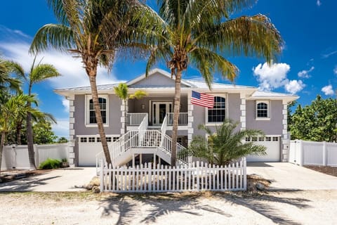 Luxury Coastal Vacation Home Exterior on Manasota Key with Private Beach Access and Palm-Lined Driveway