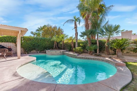This stunning backyard oasis features a sparkling in-ground pool with a built-in spa, perfect for re