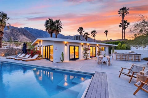 Sunset-kissed exterior view highlighting the pristine pool, expansive patio, and iconic mountain silhouettes.