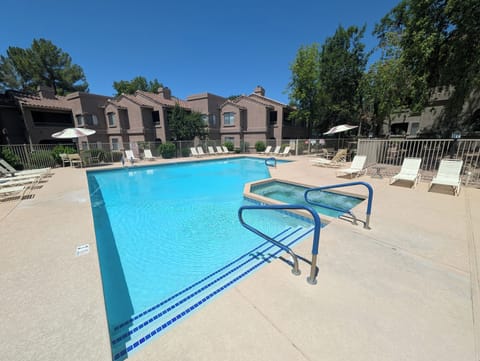 Sunny resort-style pool and hot tub with ample loungers