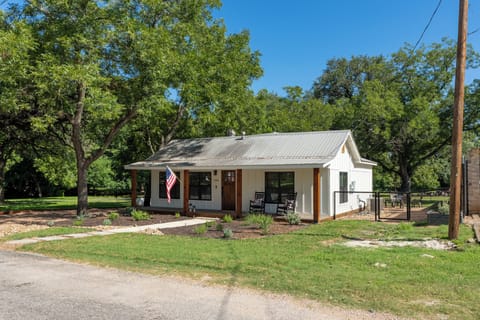 Charming cottage with shaded porch, rocking chairs, and peaceful yard