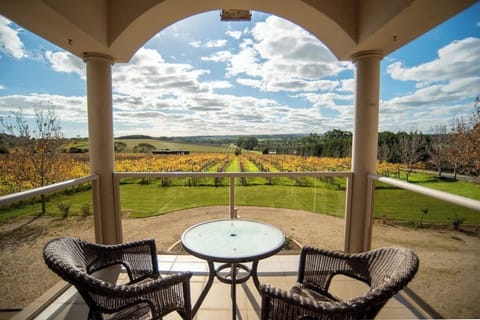 Private master bedroom balcony with seating for two and uninterrupted vineyard panorama.