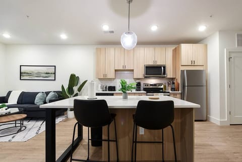 Contemporary kitchen with island seating, sleek cabinetry, and a cozy living area nearby.