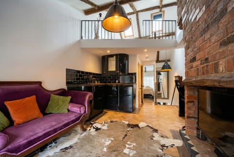 Exposed beams, velvet sofa, and mezzanine above tell the story of this one-of-a-kind space.