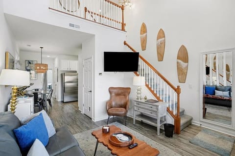 Vaulted living room with surfboard wall, smart TV, and light-filled bay windows