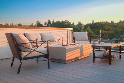 Sunset rooftop lounge with fire table and treetop views