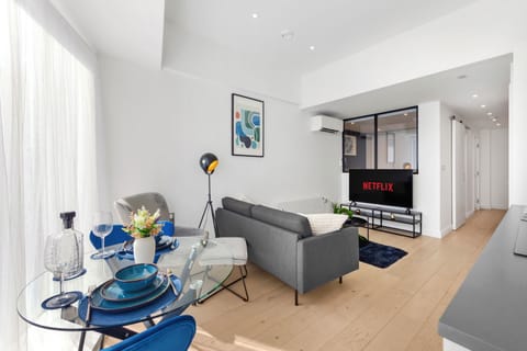 Bright modern lounge with dining area, natural light, and smart TV