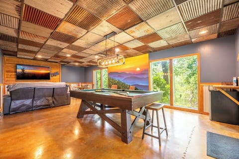 Your game room features a unique patchwork ceiling and natural light streaming through large windows. Challenge friends to pool under warm lighting, or relax on the cozy sofa—a perfect retreat for fun and connection.
