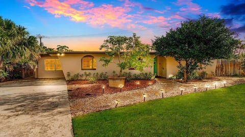 Full outdoor shot of a single-story beige house with a light teal front door.