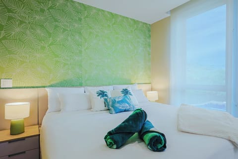 Drift off beneath tropical-inspired walls, wrapped in crisp white linens, your serene retreat awaits.