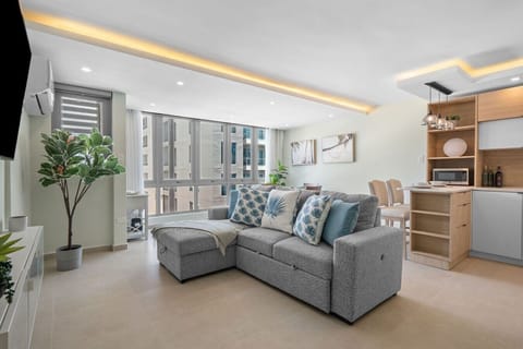 Spacious living area with a comfortable sectional sofa, Smart TV, and abundant natural light.
