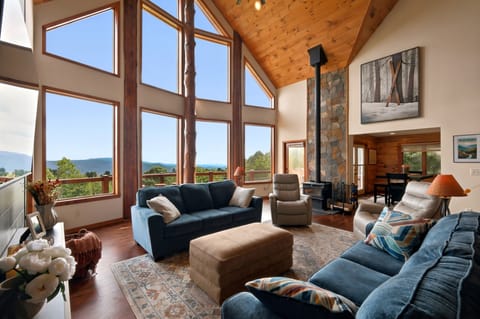 Sink into deep sofas beneath a two-story wall of windows, warmed by the wood stove on its stacked stone hearth, with the Blue Ridge spread out beyond the glass.