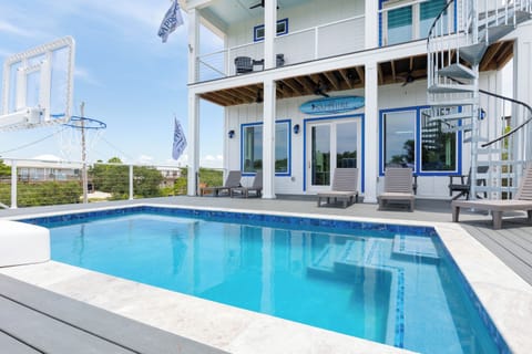 Spacious multi-level pool deck with tanning chairs, basketball hoop, and balcony view of the gulf.