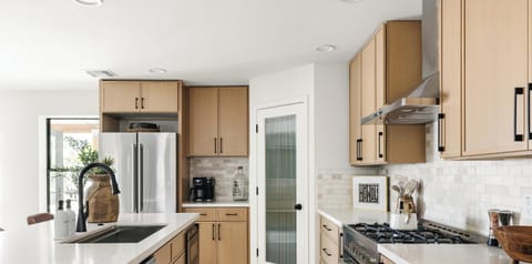 Bright modern kitchen with gas range, quartz counters, and sleek finishes