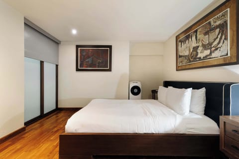 Cozy bedroom featuring a comfortable bed, warm wood floors, and elegant artwork.