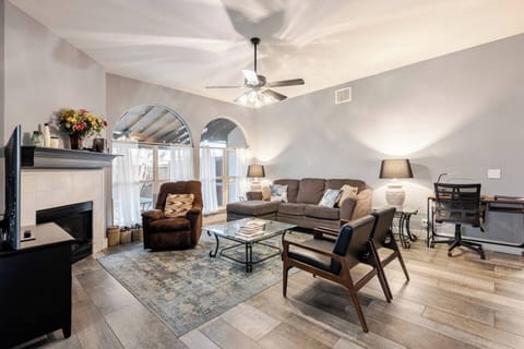 This inviting living room blends comfort and style with plush seating, warm lighting, and a cozy fireplace. The large arched windows provide a beautiful view of the patio, creating a serene and relaxing ambiance for your stay. 