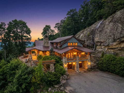 At blue hour every window glows against the granite cliff this house is built into, the private waterfall still catching the day's last light.