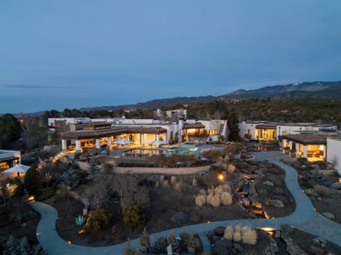 Stunning modern estate nestled in mountainous landscape with dramatic evening lighting and luxurious outdoor spaces.