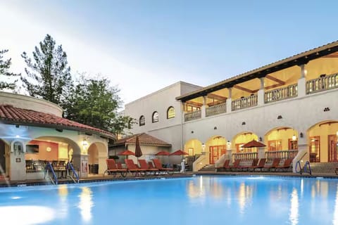 Unwind poolside at dusk with glowing arches and loungers.